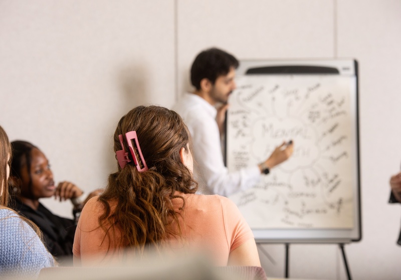 People looking at a man writing on a flip chart
